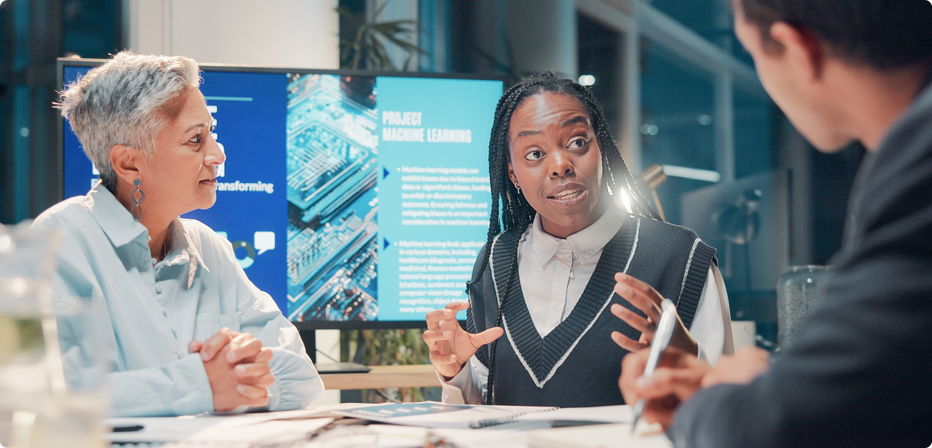 Group discussion around AI and machine learning concepts, with a screen displaying technical content during a podcast-style conversation
