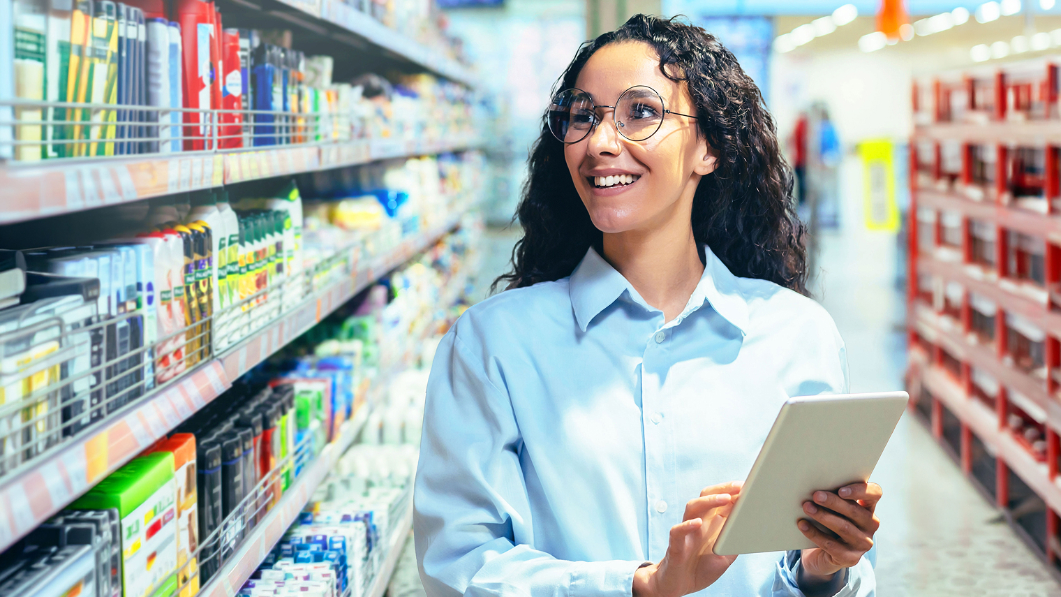 Sales rep with a tablet looking at packaged goods on the shelf.