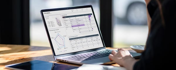 Laptop displaying an LCA dashboard with a spider chart and data tables, viewed at an angle on a table.